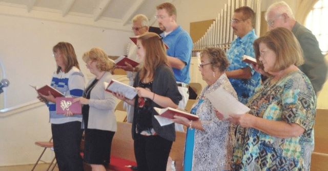 Choir members singing from hymnals during worship