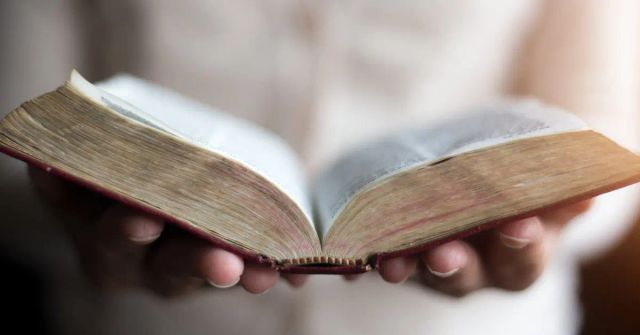 Hands holding an open Bible